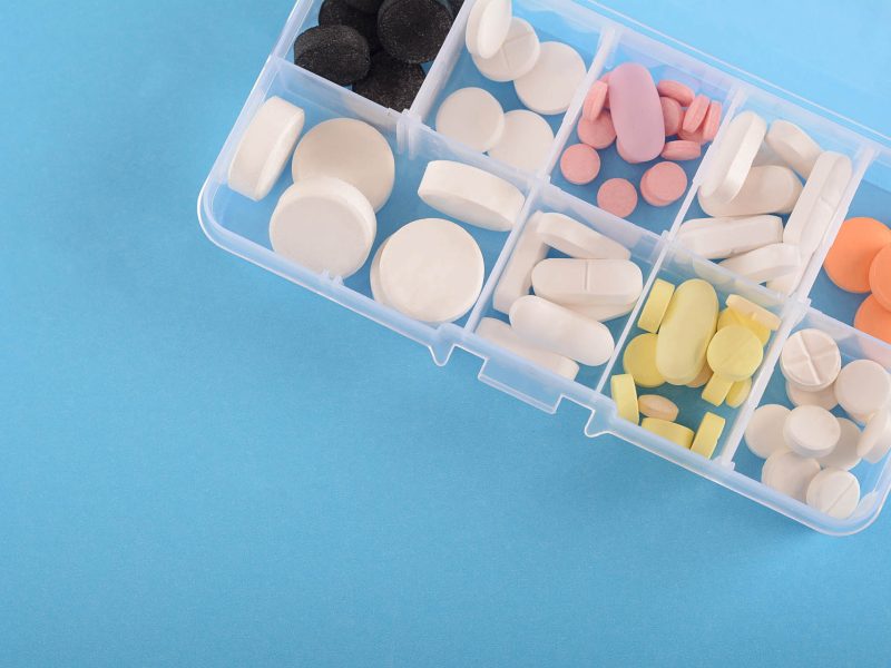 Close up of pills with medicine box. Light blue background. Medicine concept